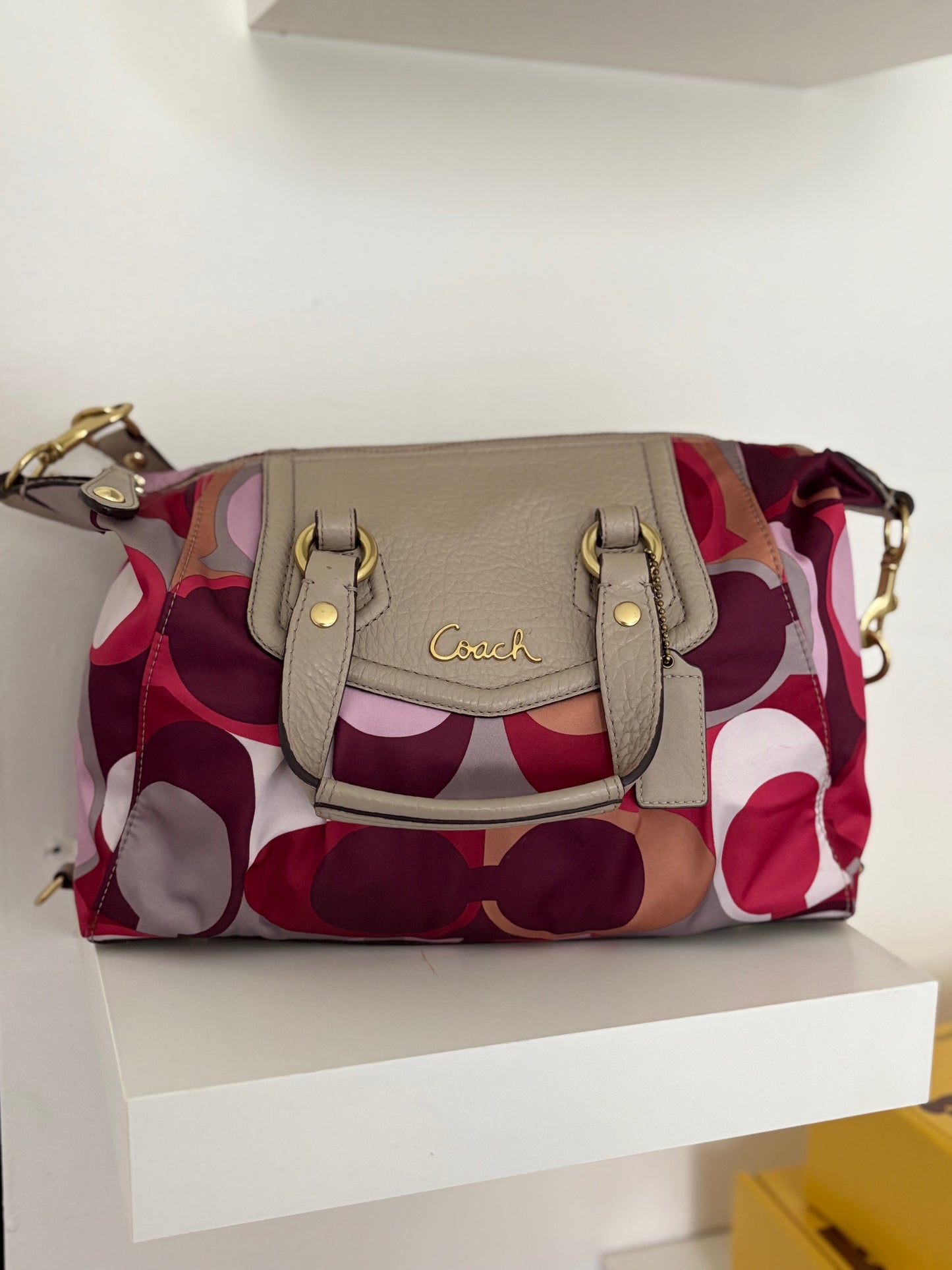 A bold and playful statement piece, this Coach Poppy Glam Tote features a glossy multicolor satin body in shades of chocolate, gold, and beige, accented with silver-tone hardware. The round “Coach Est. 1941” emblem gives it a signature touch, while the lightweight and roomy design makes it perfect for everyday wear.