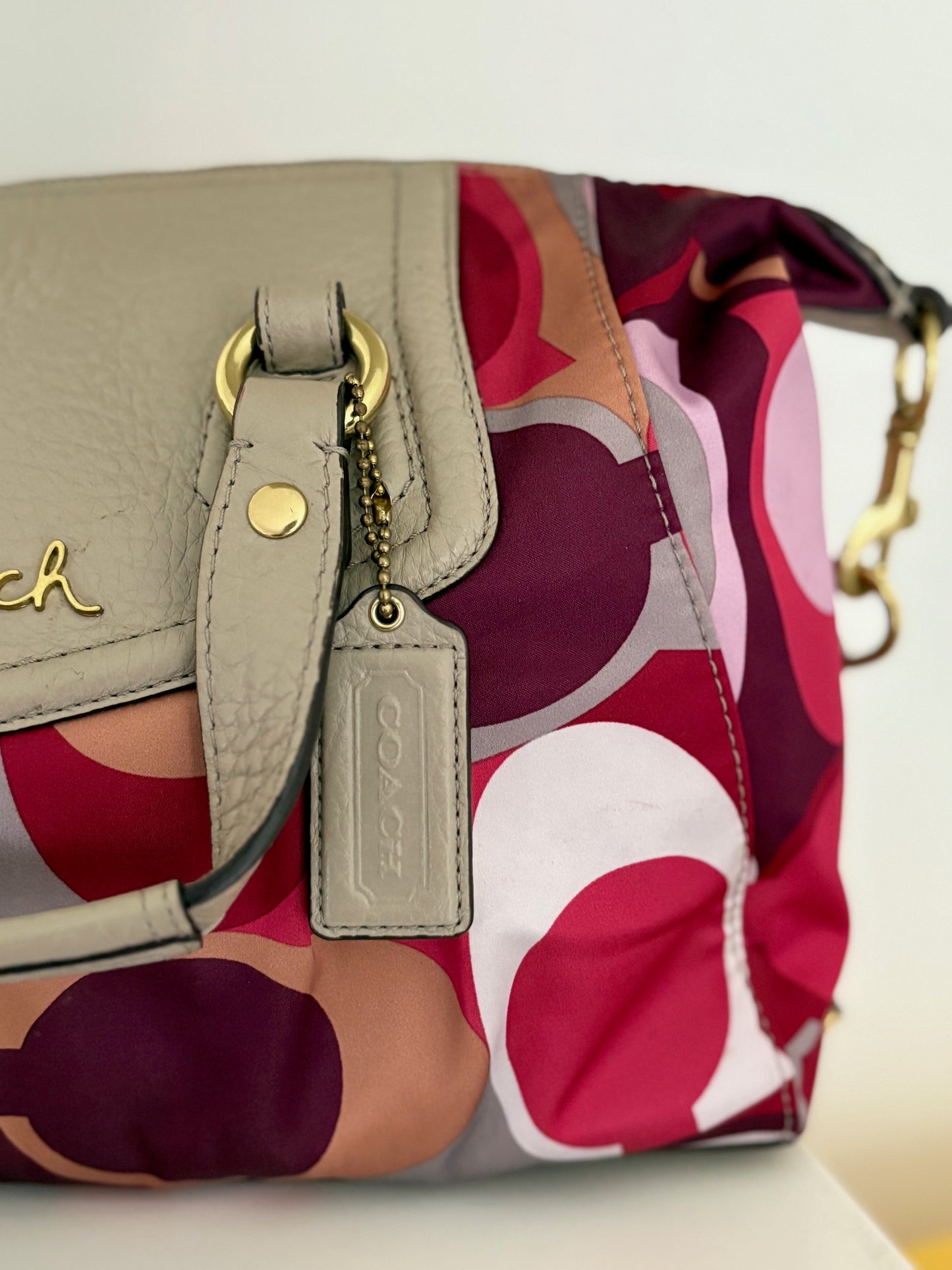 A bold and playful statement piece, this Coach Poppy Glam Tote features a glossy multicolor satin body in shades of chocolate, gold, and beige, accented with silver-tone hardware. The round “Coach Est. 1941” emblem gives it a signature touch, while the lightweight and roomy design makes it perfect for everyday wear.