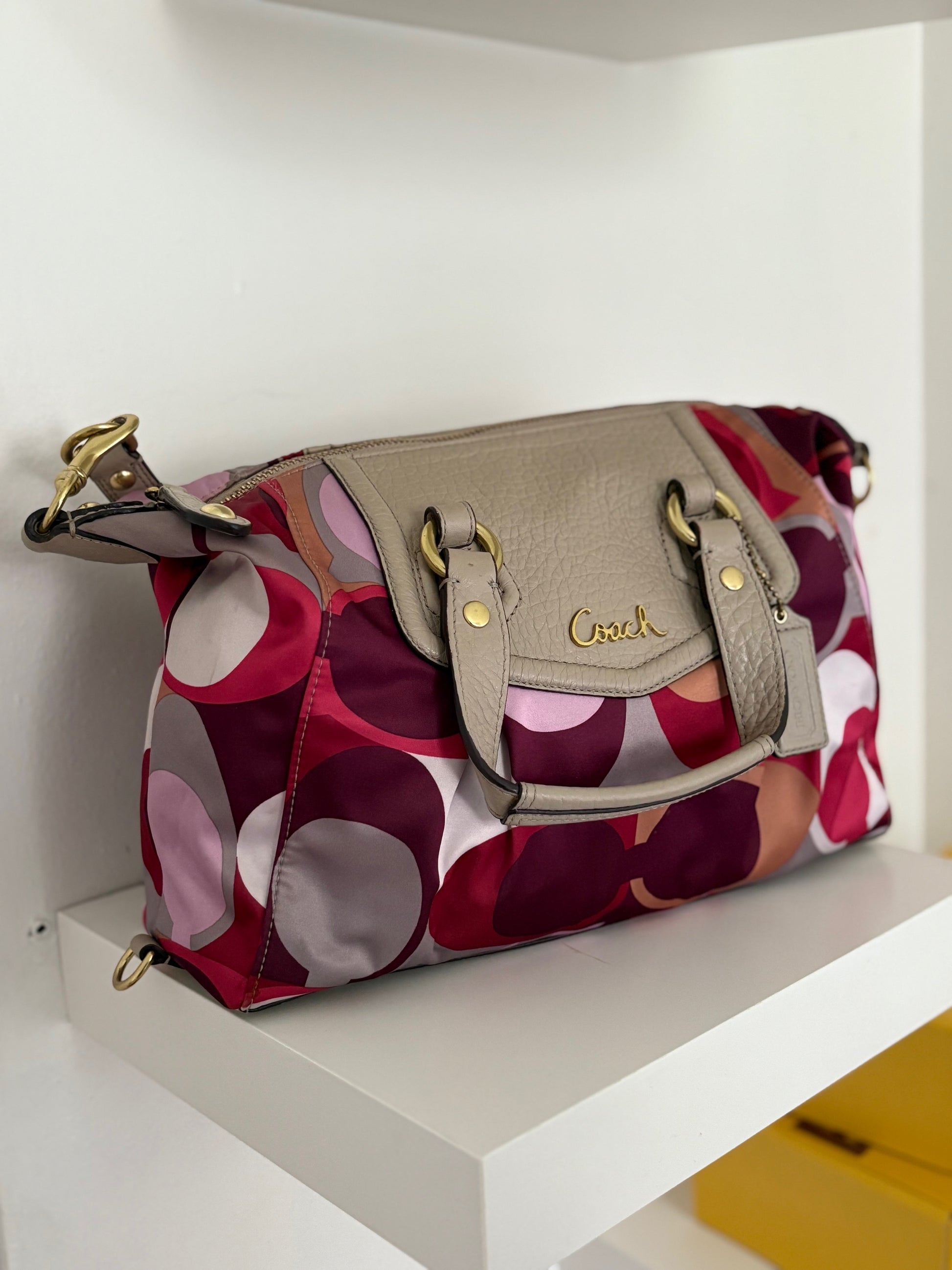 A bold and playful statement piece, this Coach Poppy Glam Tote features a glossy multicolor satin body in shades of chocolate, gold, and beige, accented with silver-tone hardware. The round “Coach Est. 1941” emblem gives it a signature touch, while the lightweight and roomy design makes it perfect for everyday wear.