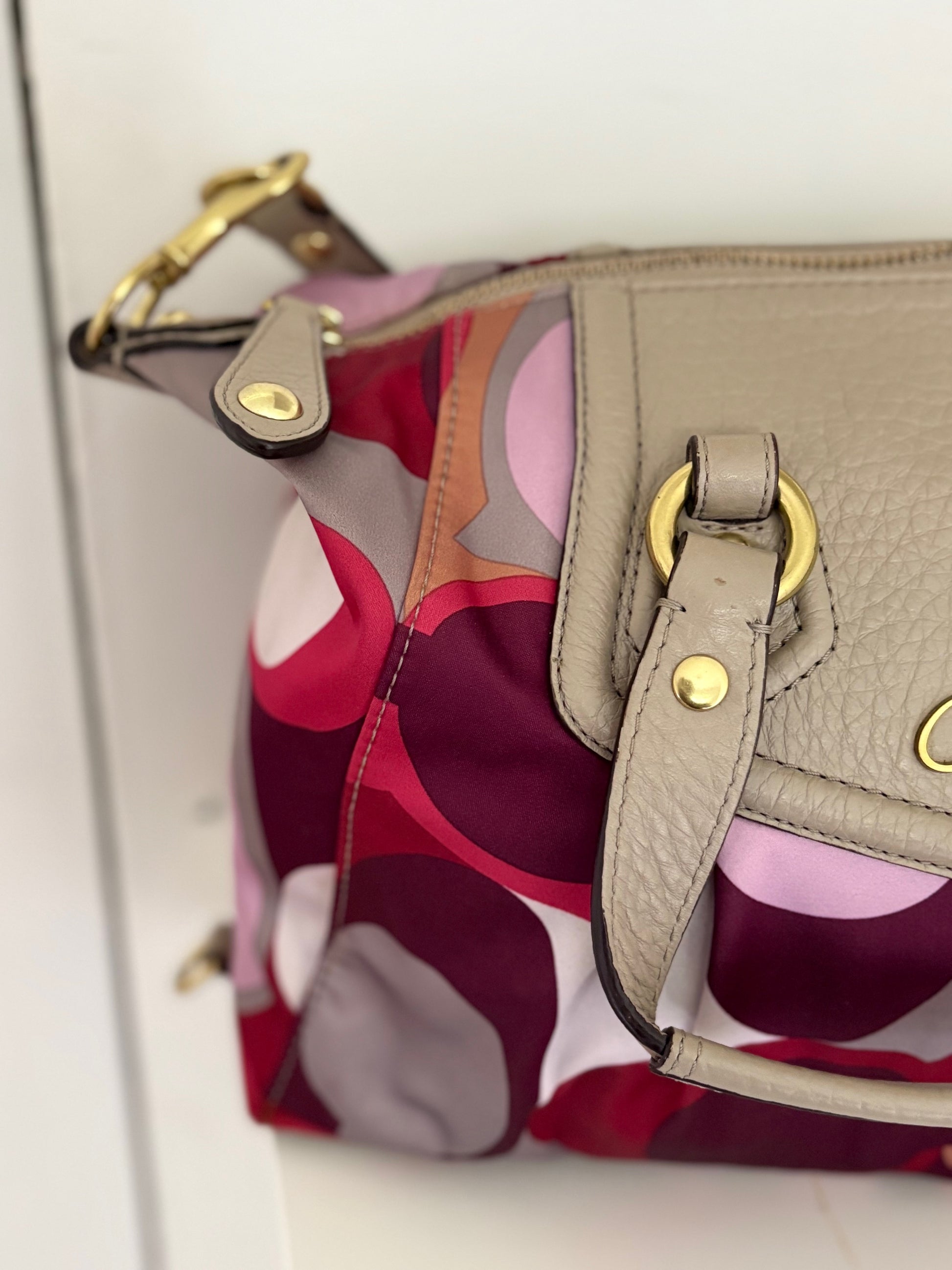 A bold and playful statement piece, this Coach Poppy Glam Tote features a glossy multicolor satin body in shades of chocolate, gold, and beige, accented with silver-tone hardware. The round “Coach Est. 1941” emblem gives it a signature touch, while the lightweight and roomy design makes it perfect for everyday wear.